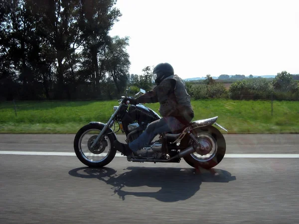 骑摩托车的人骑着切割机在公路上的树木和乡村模糊的背景下行驶 — 图库照片