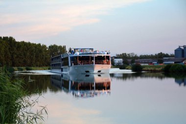 Büyük bir turist gemisi kıyılar arasındaki sakin nehir boyunca yelken açıyor. Yaz nehir seyahatleri