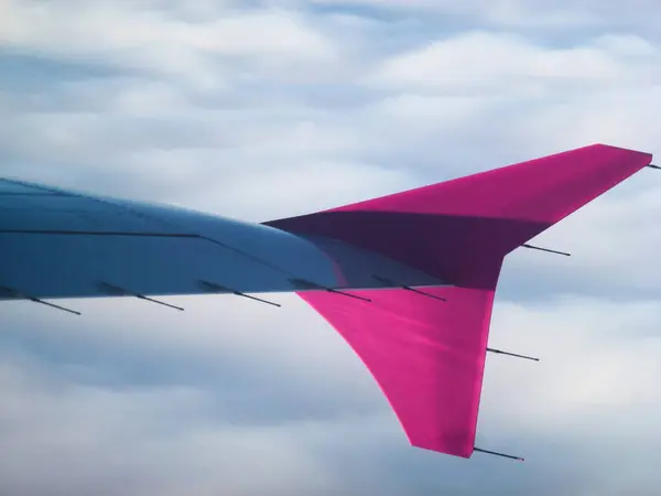 Część Skrzydła Samolotu Pasażerskiego Różowym Stabilizatorem Lecącym Nad Białymi Chmurami — Zdjęcie stockowe