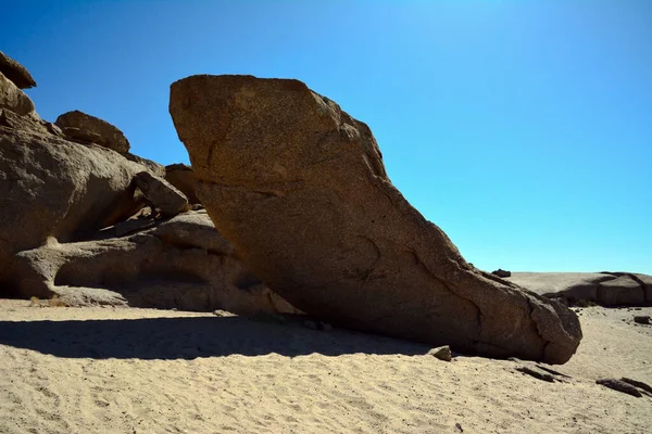 在明亮的阳光下 蓝色天空的背景下 巨大的巨石巨石躺在沙漠的沙滩上 — 图库照片