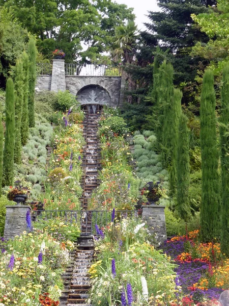 公园里的手工装饰瀑布 它的两侧有许多花和绿叶 该地区的景观设计和绿化 — 图库照片