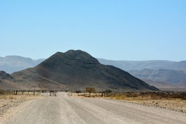 Kurak çöl bölgesinde dağların önünde açık mavi gökyüzüne karşı özel mülk çitlerini yasaklamak