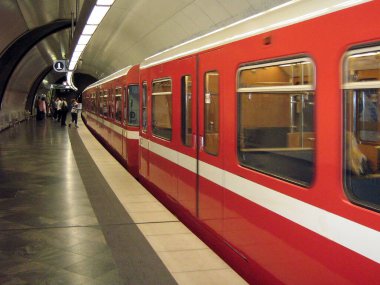 Yeraltı istasyonundaki elektrikli metro treninin kırmızı vagonları perspektif olarak. Tanımlanamayan yolcular,