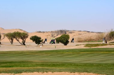 Birkaç spor turisti çölün yakınındaki golf sahalarına doğru yürüyorlar. Çevresel susuzluk ve küresel ısınma