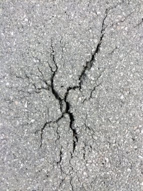 Yol yüzeyindeki eski asfaltta farklı yönlere bölünmüş bir çatlak. Üst görünüm