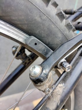 Eski bir bisiklet tekerinin fren yastığı. Tekerleğin bir kısmı görünür.