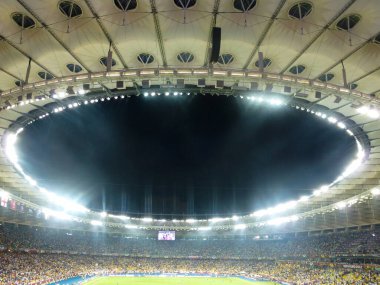 Ortasında delik olan büyük bir futbol stadyumunun parlak ışıklı çatısı. Aşağıdan görüntüle