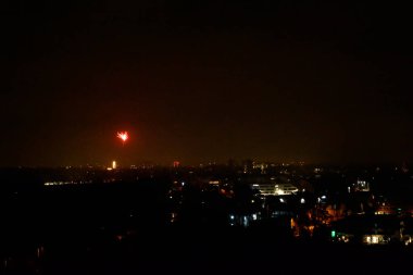 Gece şehrinde yalnız bir havai fişek patladı. Karanlık gece arkaplanı ve aydınlık evler