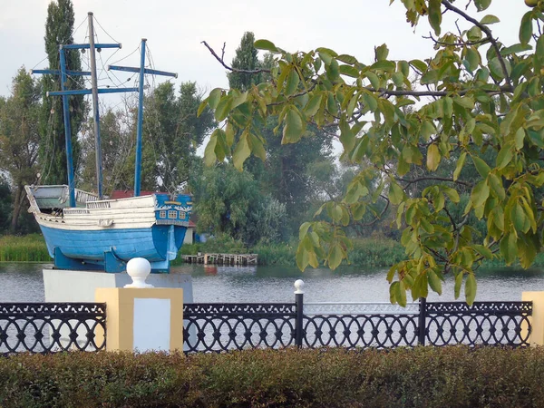 Demirden bir çitin arkasındaki şehir parkındaki nehir kıyısındaki bir yelkenli gemisinin anıtı.