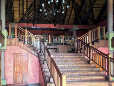 İkinci katta parmaklıkları olan geniş tahta merdivenler. Odanın içi ahşap dekore edilmiş.