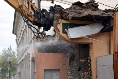 Modern bir şehrin caddesindeki bir binayı kazıcı kullanarak sökmek. Şehirlerin yeniden inşası ve yenilenmesi
