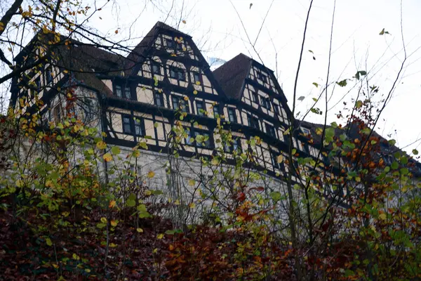 An old hotel building is visible through the bushes of a park in England, Great Britain. The building is located on a hill