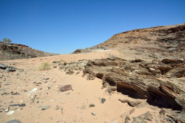 Uzak kayalık dağları olan çöl manzarasında akşam gökyüzüne karşı büyük kayalar. Doğal çevreyi çevreleyen çorak