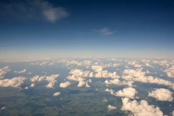 View from the sky above the clouds to the surface of the earth to the horizon on the background of the blue sky. Natural atmospheric landscape
