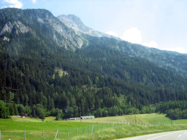 Hızlı giden bir yoldaki bir arabadan dağların manzarası. Parlak güneşin altında doğal bir manzara.