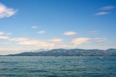 Açık bir gökyüzünün altında, deniz kenarından çok uzaktaki orman dağları olan uzak kıyı şeridi. Yaz turist manzarası