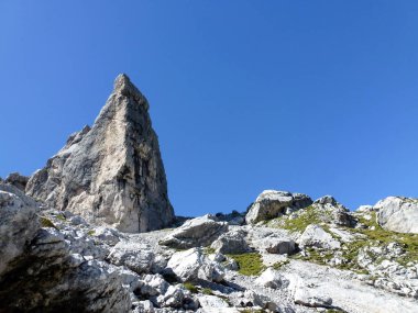 A view of the rocks of mountains illuminated by the sun under a clear blue sky. View from below. Mountain summer tourist landscape