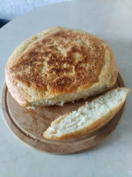 Büyük bir parça kesilmiş ev yapımı yuvarlak ekmek ahşap bir tabakta yatıyor. Yukarıdan bak. Kendi ellerinle ev yapımı pişirme.