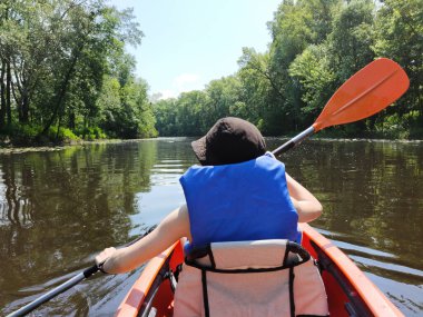 Genç bir çocuk nehirde şapkayla kayak yapıyor. Ağacın kenarlarında. Dikiz aynası. Spor ve aktif bir yaşam tarzı
