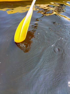 Nehrin sularındaki teknenin sarı küreği ve güneşin yansımaları. Üst Manzara. Minimalizm ve soyutlama