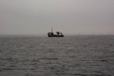 Akşam denizinde eski bir balıkçı yelkenlisi yelken açar. Deniz manzarası ve deniz taşımacılığı
