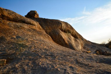 Kuru ve ıssız bir çöldeki kayalık bir tepe mavi gökyüzünün arka planına karşı. Kuru yaz sıcağı ve vahşi doğa.