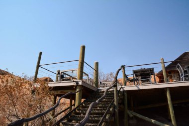 Çöldeki bungalov otelinin ahşap platformuna giden merdivenler açık gökyüzünün altında. Aşağıdan görüntüle