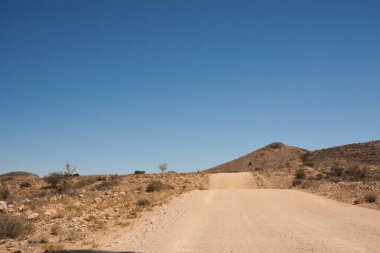 Gökyüzünün altındaki küçük tepelerin arasında boş bir yolun manzarası.
