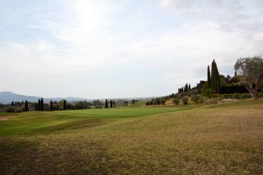 Uzakta çimleri ve dağları olan büyük golf sahaları. Çimler kısa kesilmiş.
