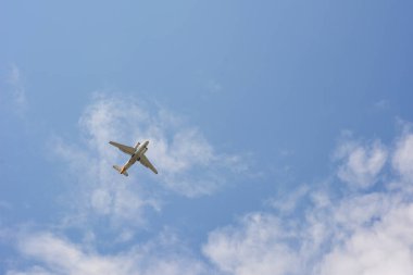 Bir yolcu uçağı açık bulutlu mavi gökyüzünde yükseklerde uçar. Yolcu taşımacılığı ve havayolları