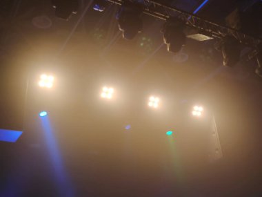 Aşağıdan parlak bir konser sahnesinin görüntüsü. Sadece karanlık konser salonunun tavanı görünüyor.