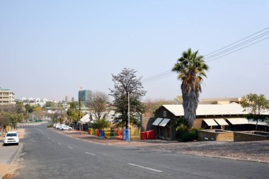 Kenarlarında ve ağaçlarında küçük banliyö evleri olan bir yol manzarası. Kenar mahalle gelişimi ve mimarisi