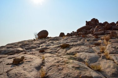 Parlak, berrak bir gökyüzünün arka planında büyük kaya parçaları çöldeki kayalık bir tepenin yamacına saçılmıştır. Aşağıdan bak. Kurak iklim ve aşırı topraklar