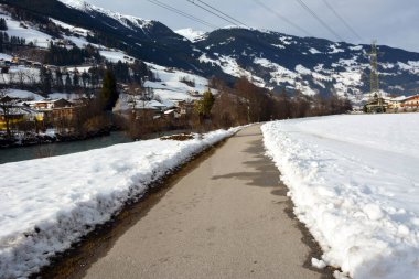 Dağın altındaki kış köyünün yolu. Kenarlarda çok kar var.