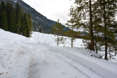 Dağın altındaki kış köyünün yolu. Kenarlarda çok kar var.