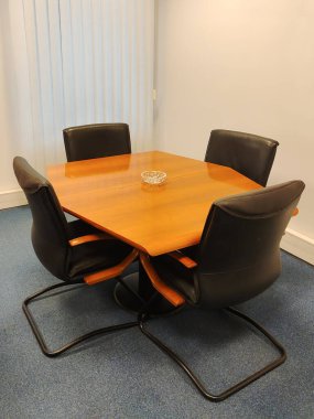 Ofiste, ahşap bir ofis masasının etrafında tartışılacak dört rahat sandalye var. Masada sadece bir kül tablası var. Ofisin içini gösteren bir örnek.