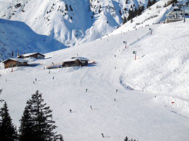 Kayakçıların ve snowboardcuların indiği geniş kış kayak pistinin manzarası. Uzaktan bir manzara. Kış sporları ve eğlence