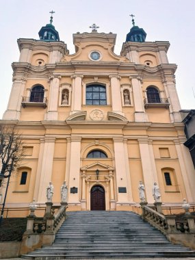 Resimli sarı bir Katolik kilisesinin dış görünüşü ve merdivenleri. Tarihsel ve dini miras. Alt görünüm