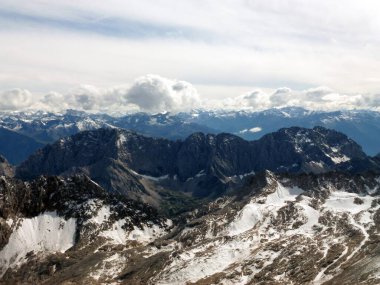 Kar kaplı yüksek dağlardan ufuk çizgisine kadar beyaz bulutların altında manzara. Kış manzarası ve vahşi yaşam