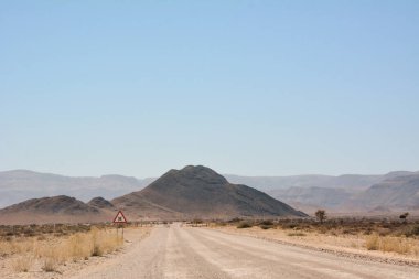 Mavi gökyüzüne karşı çöl tepeleri arasındaki toprak yol. Çöl manzarası ve çevresi