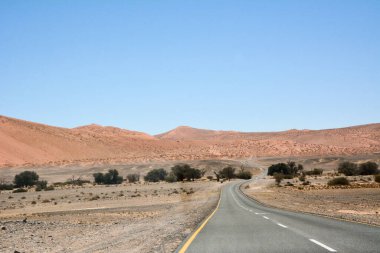 Mavi gökyüzüne karşı çöl tepeleri arasındaki toprak yol. Çöl manzarası ve çevresi