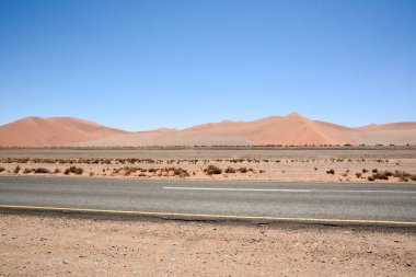 Çölde asfalt yol manzarası. Açık mavi gökyüzünün altındaki küçük kumullar. Çöl turist manzarası