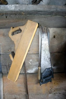 Eski el testeresi ve marangozluk için uçak ahırdaki ahşap duvara asılıydı. Vintage araçlar ve köy içi