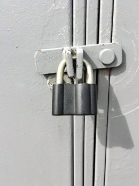 Özel mülkün kapalı kapısında asılı asma kilit gri renkli. Mülk koruması ve sigortası. Kilit gölge verir