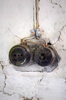 Çürük bir duvarda çift prizli elektrik prizi ve lamba anahtarı var. Elektrik kabloları üzerlerinde vidalanmış. Yerleşim yerinin mahsulü.