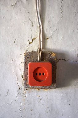 Çürük bir duvarda, üzerinde boya olan antika bir elektrik prizi. Elektrik kabloları üzerlerinde vidalanmış. Yerleşim yerinin mahsulü.