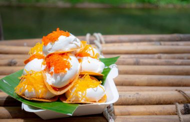 Khanom Bueng. Şekerle karıştırılmış yumurta beyazından yapılmış beyaz krema krema gibi pürüzsüz olana kadar dövülmüş. Foi tangalı garnitür ya da kızarmış karides, geleneksel Tayland tatlısı. Popüler atıştırmalıklar