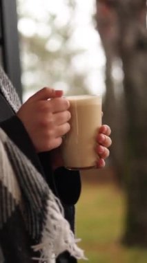 Bir adam evin yanında sıcak sıcak şarap içiyor.