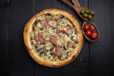 Tahta bir masada peynirli ve sebzeli lezzetli bir pizza.