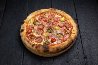 Tahta bir masada peynirli ve sebzeli lezzetli bir pizza.